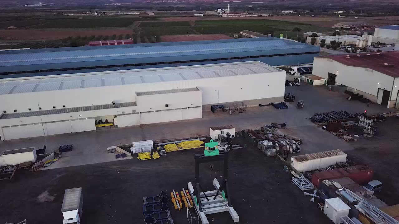 Roof of an EPER Group industrial hall with solar panels and wind turbines in the background