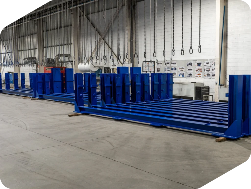 Bancadas mecano-soldadas azules alineadas en una nave industrial con cadenas colgando del techo