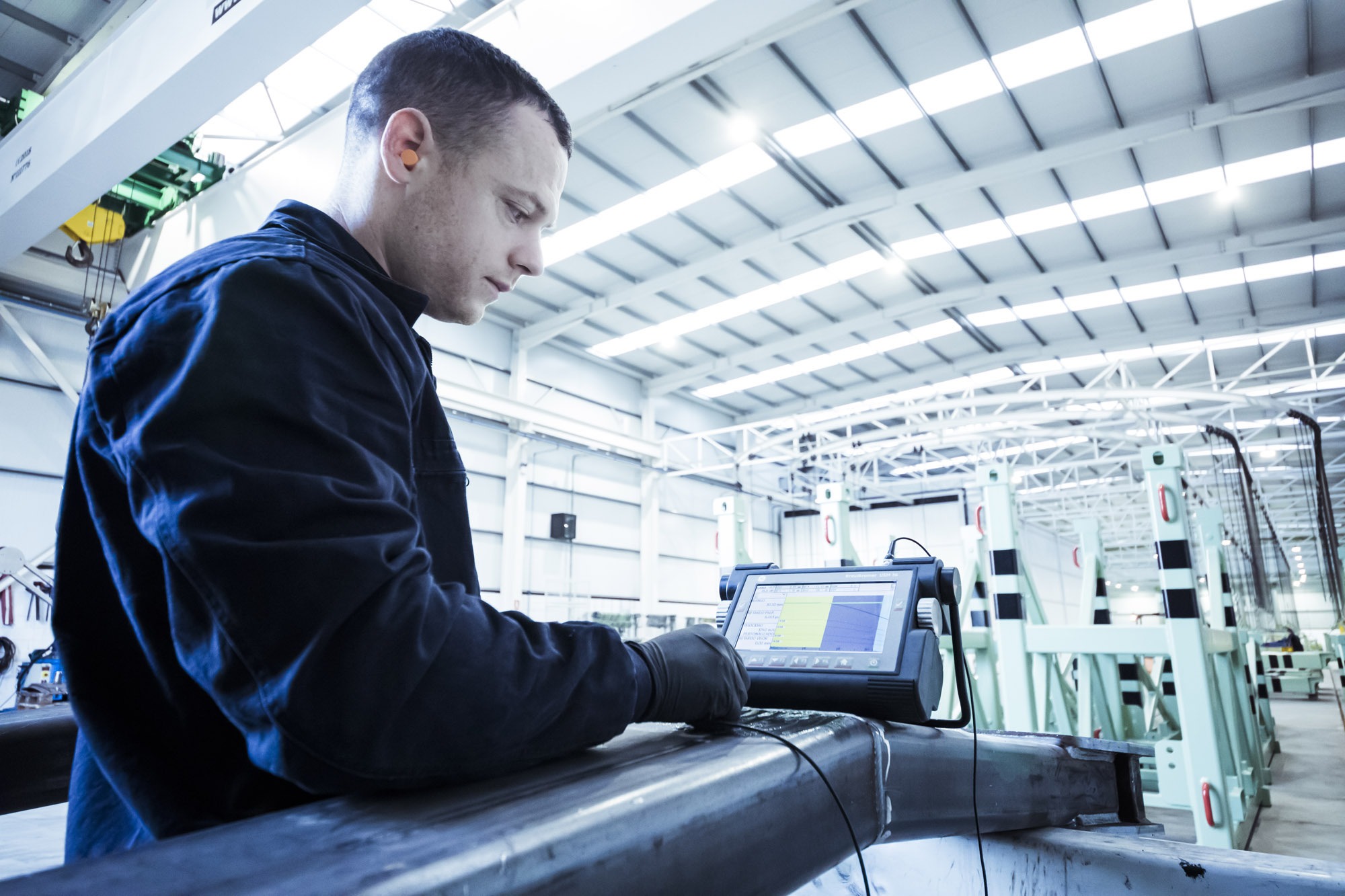 Técnico inspeccionando una pieza metálica con un equipo de ultrasonidos en una nave industrial