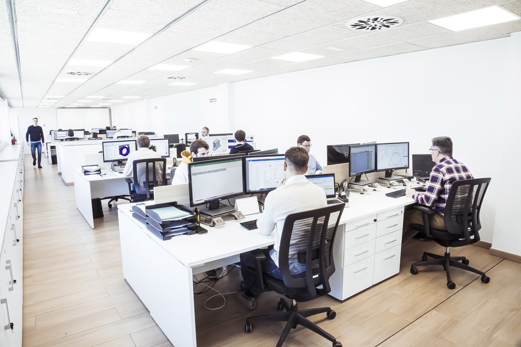 Equipo de oficina técnica trabajando con varios monitores en una oficina luminosa