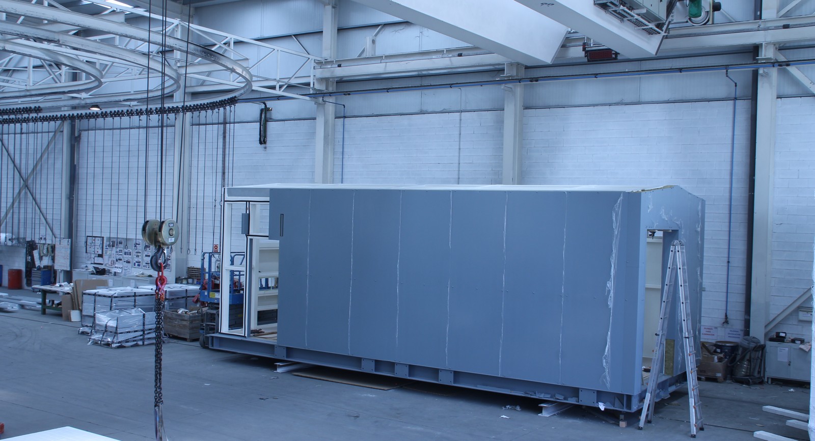 Shelter metálico gris para infraestructura tecnológica en nave de fabricación