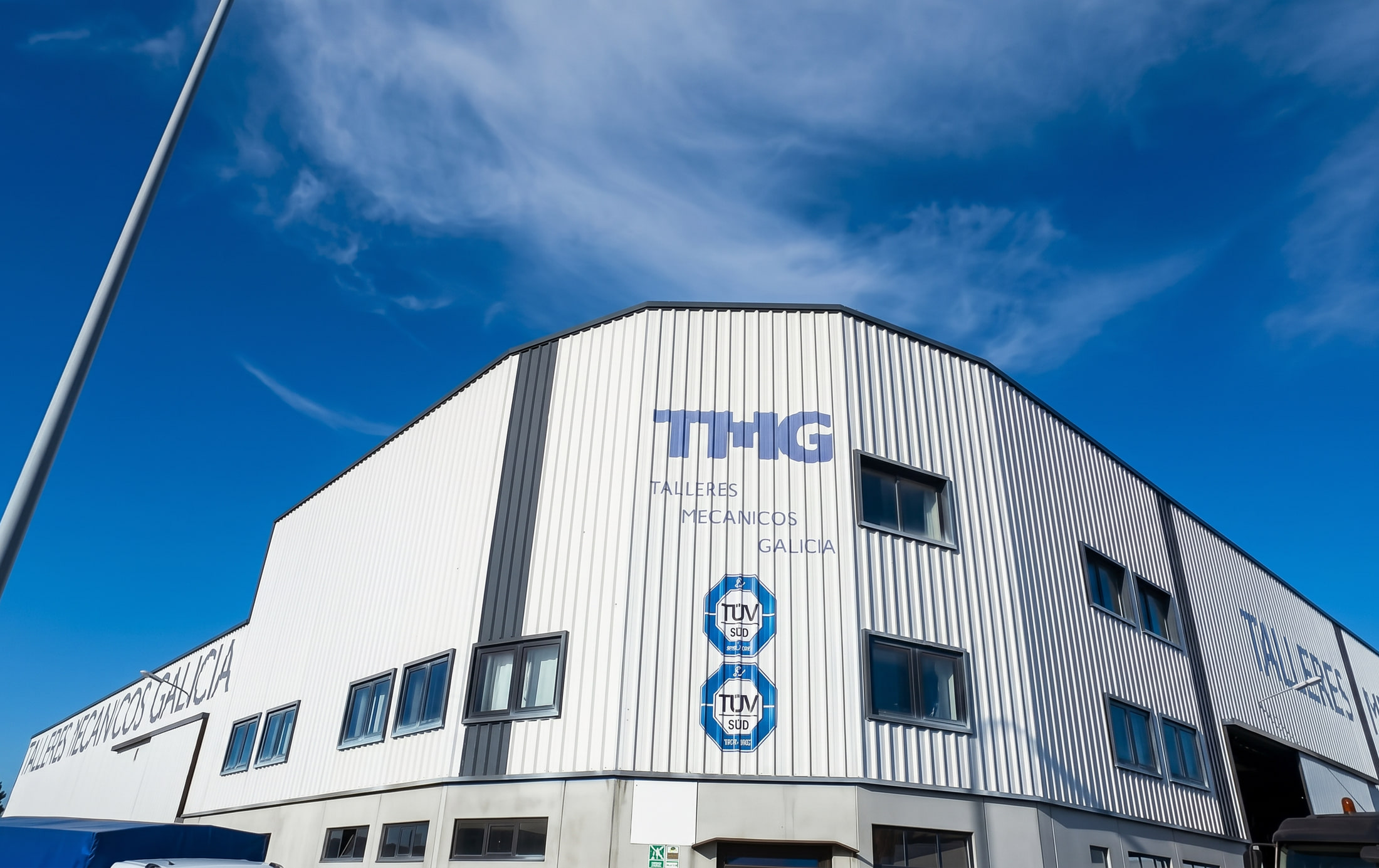 Fachada de la nave de TMG by EPER Group en Narón, A Coruña, bajo un cielo azul