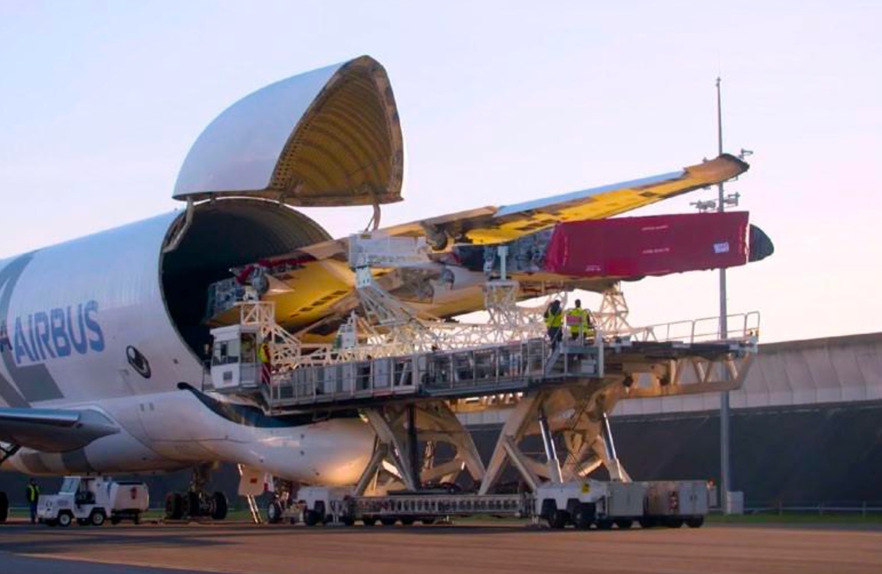 Utillaje de transporte con plataforma elevadora junto a un avión de carga