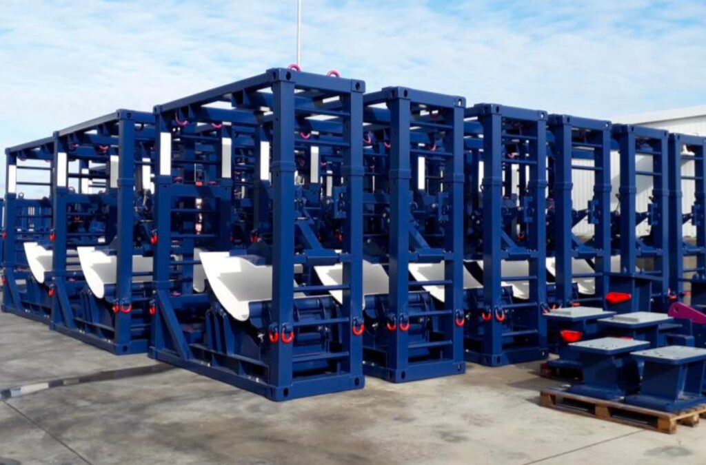 Bastidores azules de transporte con anillas rojas apilados en una explanada