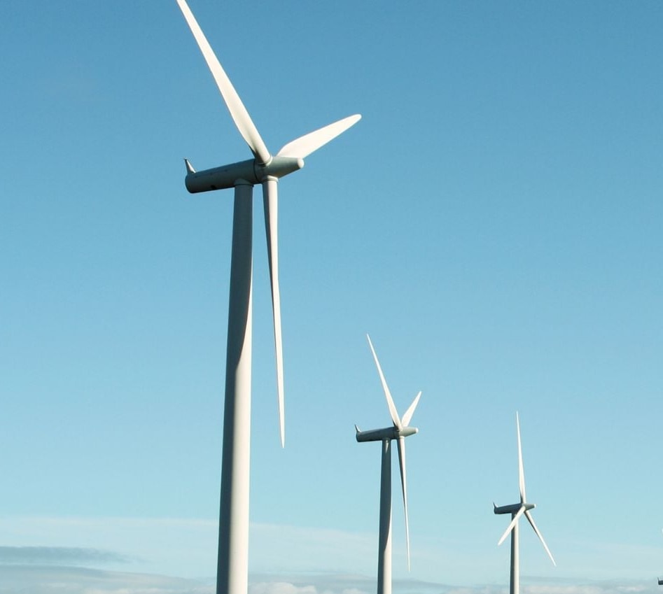 Tres aerogeneradores blancos de gran tamaño sobre un cielo azul despejado