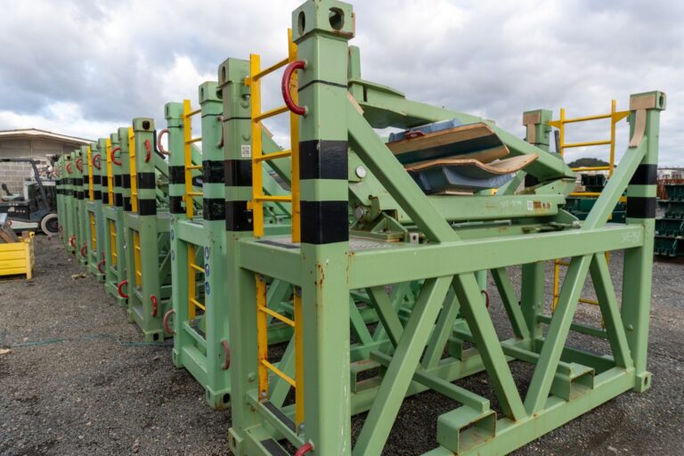 Bastidores metálicos verdes con detalles amarillos y negros almacenados en una explanada
