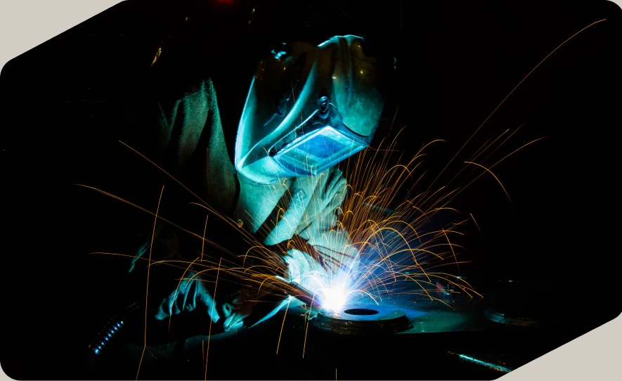Soldador con careta trabajando entre chispas y luz azul